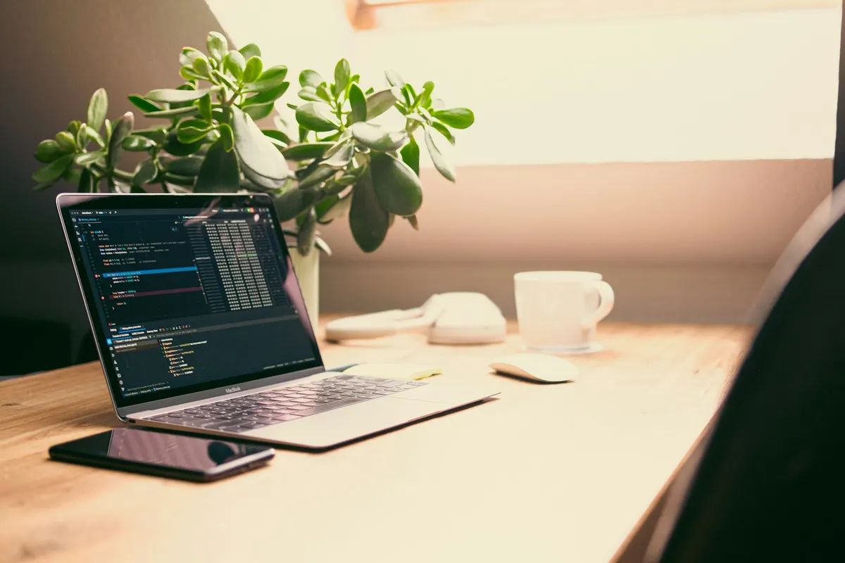 Laptop displaying code in a bright workspace